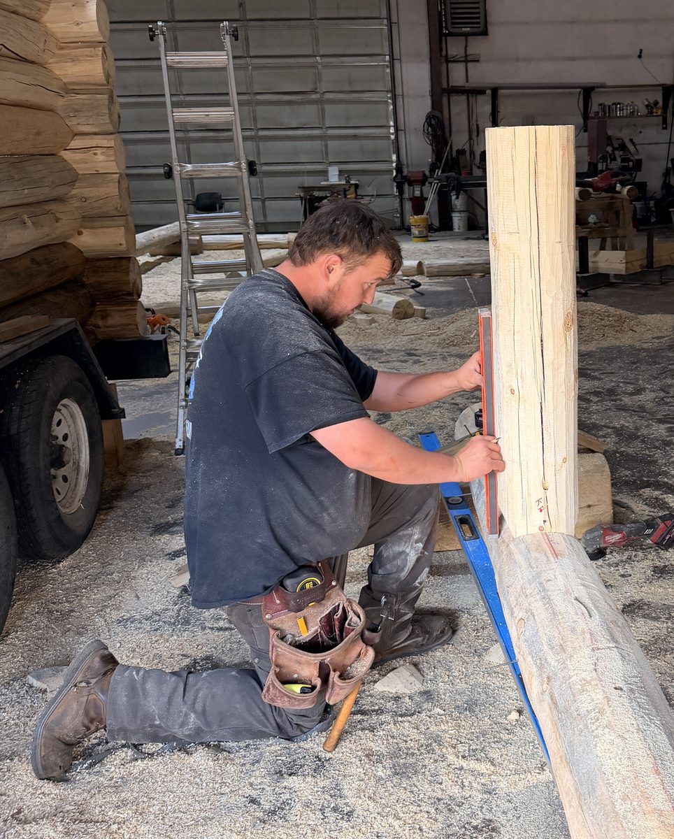 Craftsman fitting a log post in the mill shop