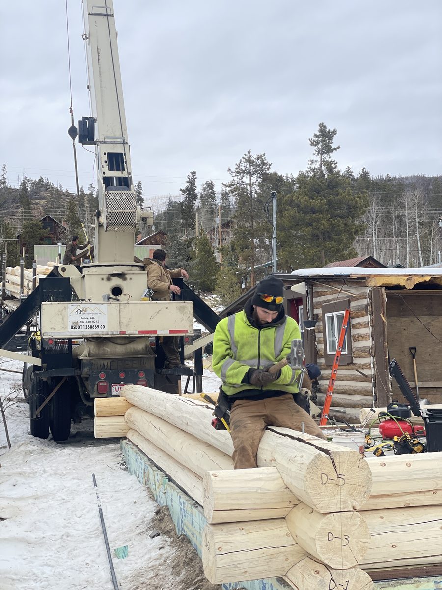 Crane setting log walls on a winter jobsite