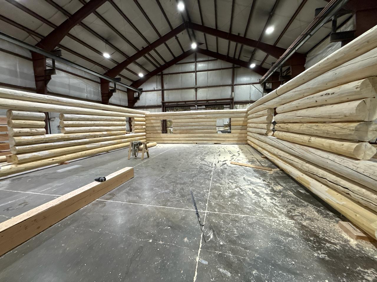 Log cabin walls stacked and numbered on the mill floor in Bailey